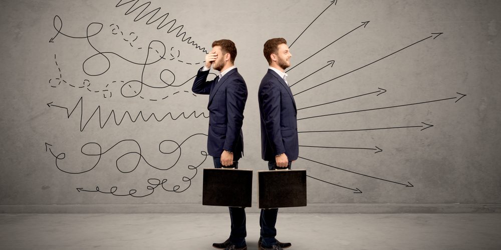 Young,Conflicted,Businessman,Choosing,Between,Two,Directions,With,Arrows,And